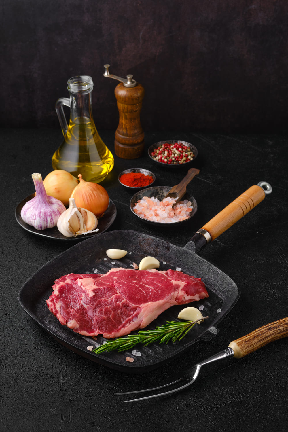 Filete de carne en sartén de hierro con condimentos y aceite de oliva.